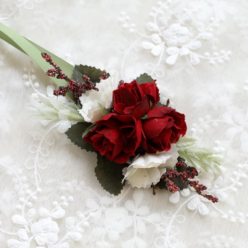 A delicate wrist corsage made of vibrant red artificial silk roses, symbolising everlasting love and beauty