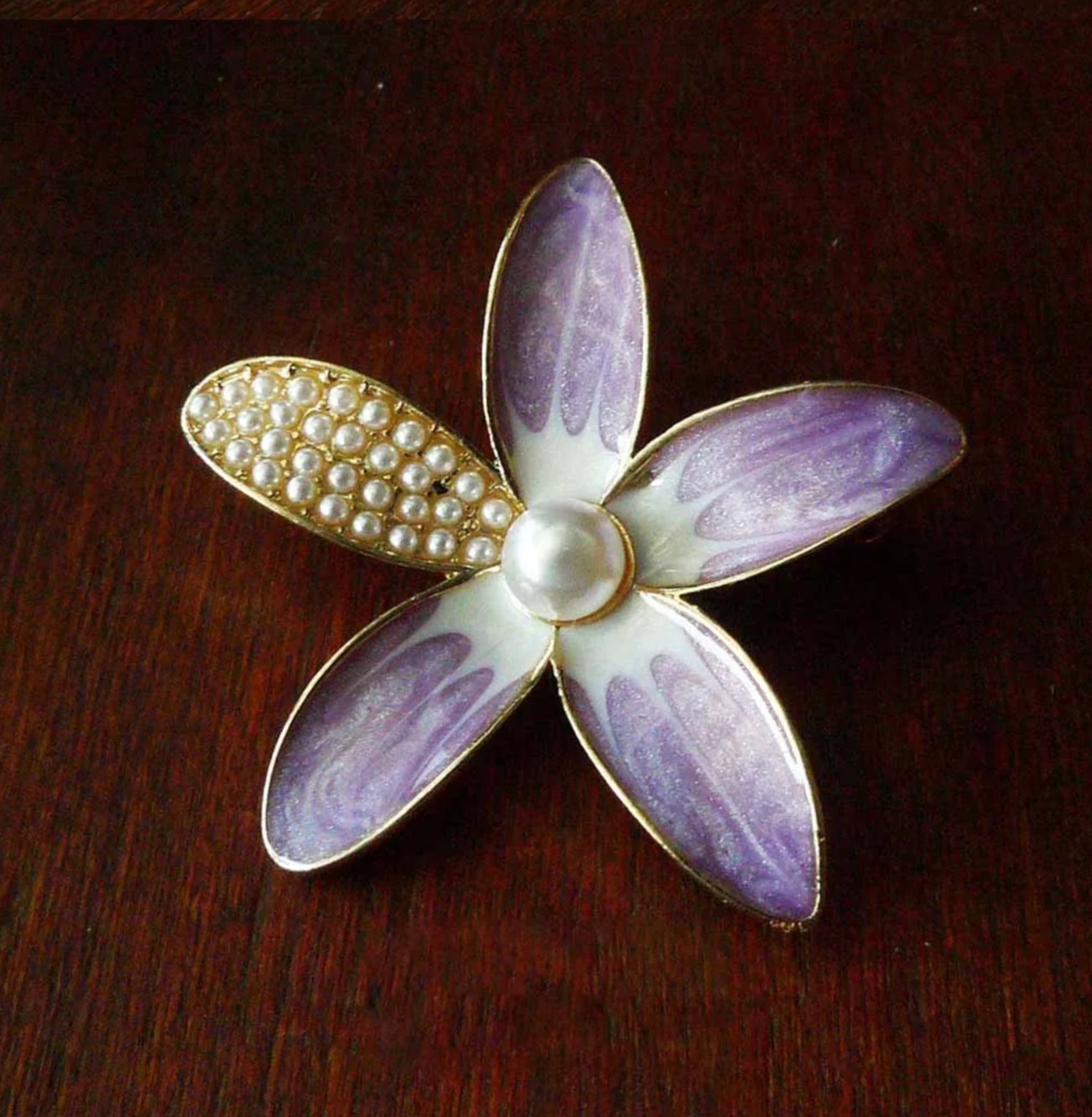 a purple and white flower brooch with pearls