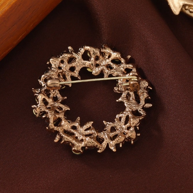 beautiful flower garland brooch adorned with burnt golden, greyish green, black, and metallic accents