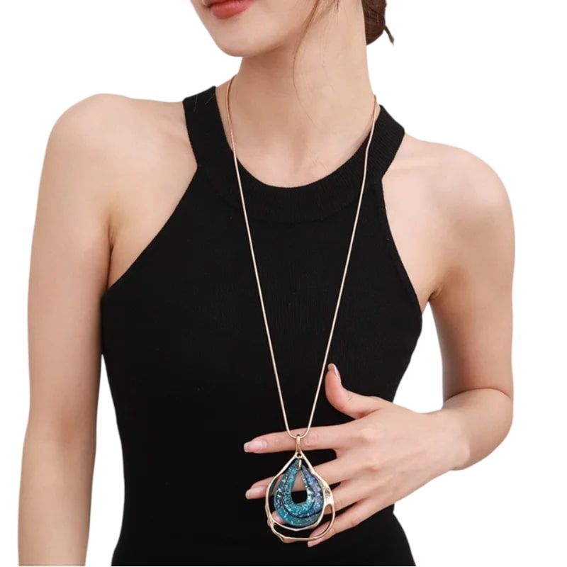 Woman in black top wearing eye-catching blue necklace with hollow water drop design.