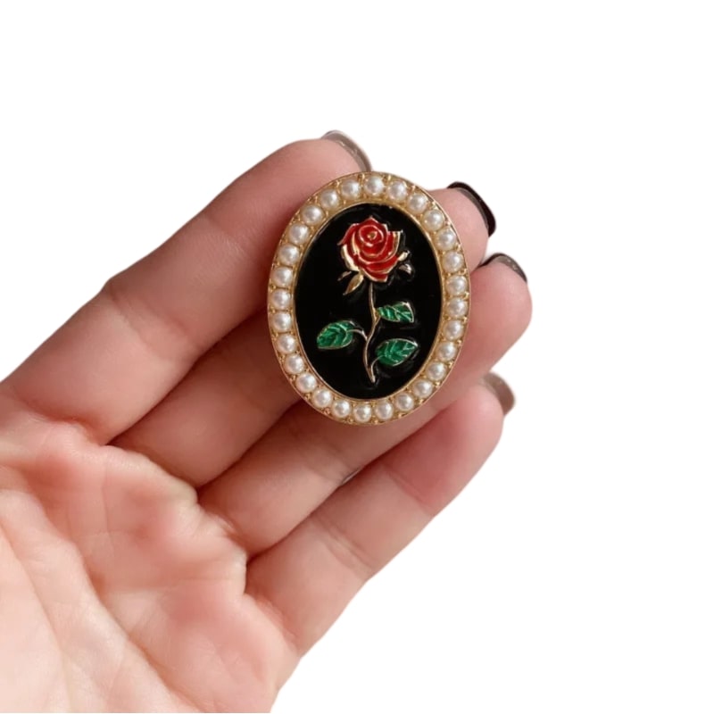 A hand holding a rose brooch with pearls, part of the Elegant French Embossed Oval Rose Pearl Brooch and earrings for women