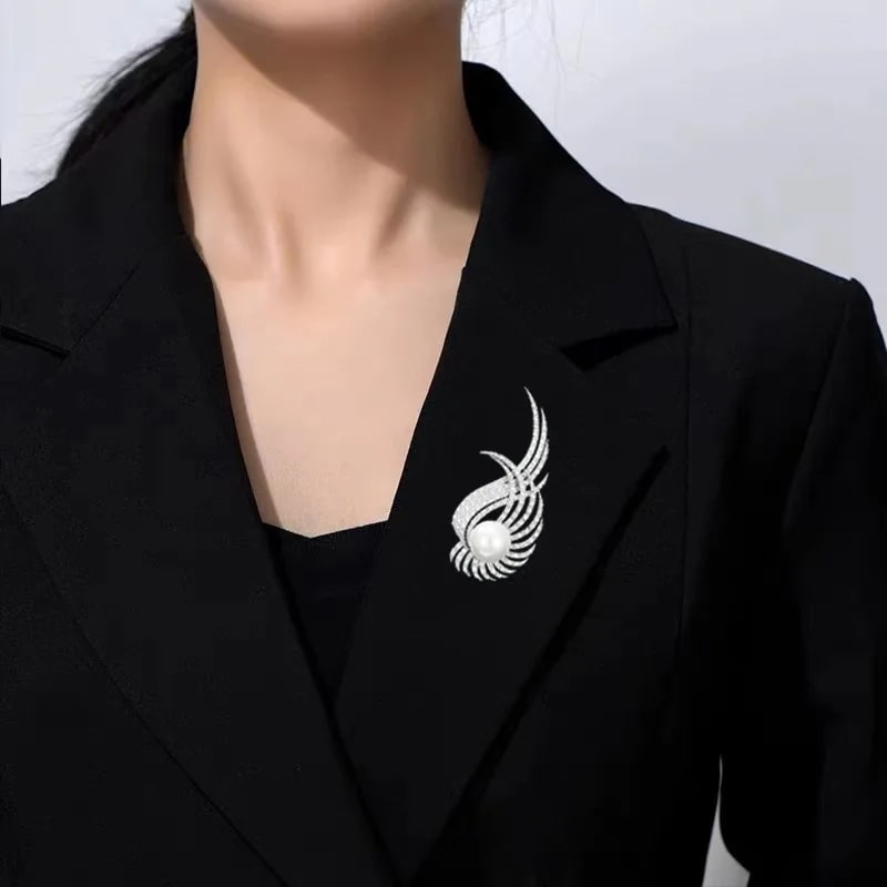 woman in black blazer with silver pin, wearing fashionable wing brooch inlaid with cubic zirconia