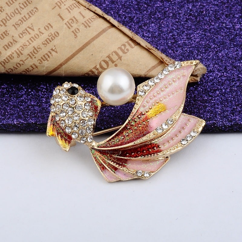 enhance your outfit with this elegant pink fish brooch, embellished with a white pearl, gold accents, and sparkling rhinestones