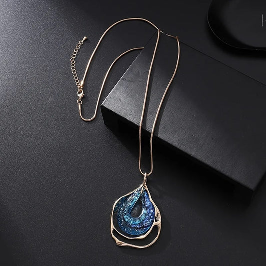 Blue and gold pendant with tear shape, showcasing a unique hollow water drop design on a delicate chain. A timeless and elegant accessory